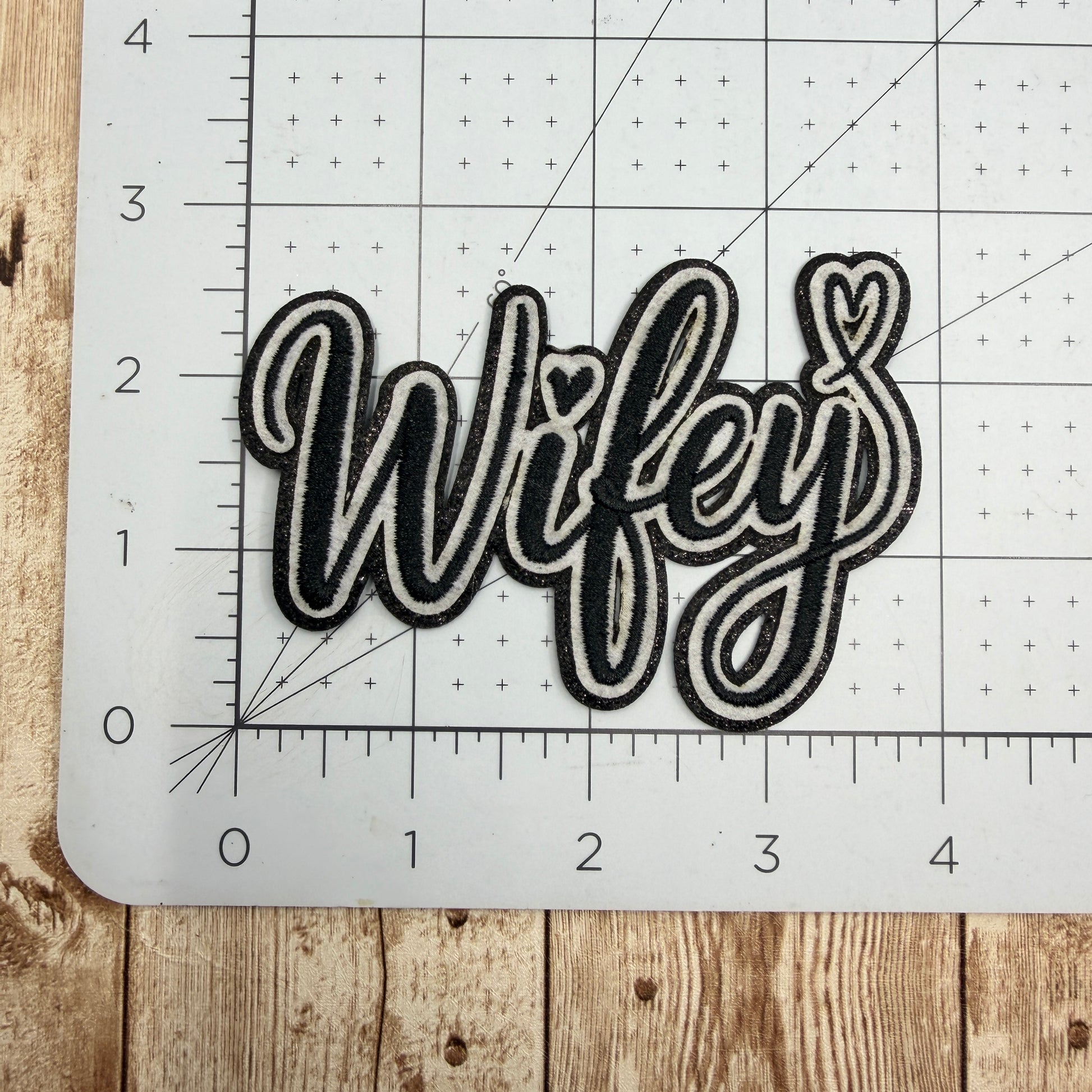 Decorative patch with 'Wifey' text on a cutting mat
